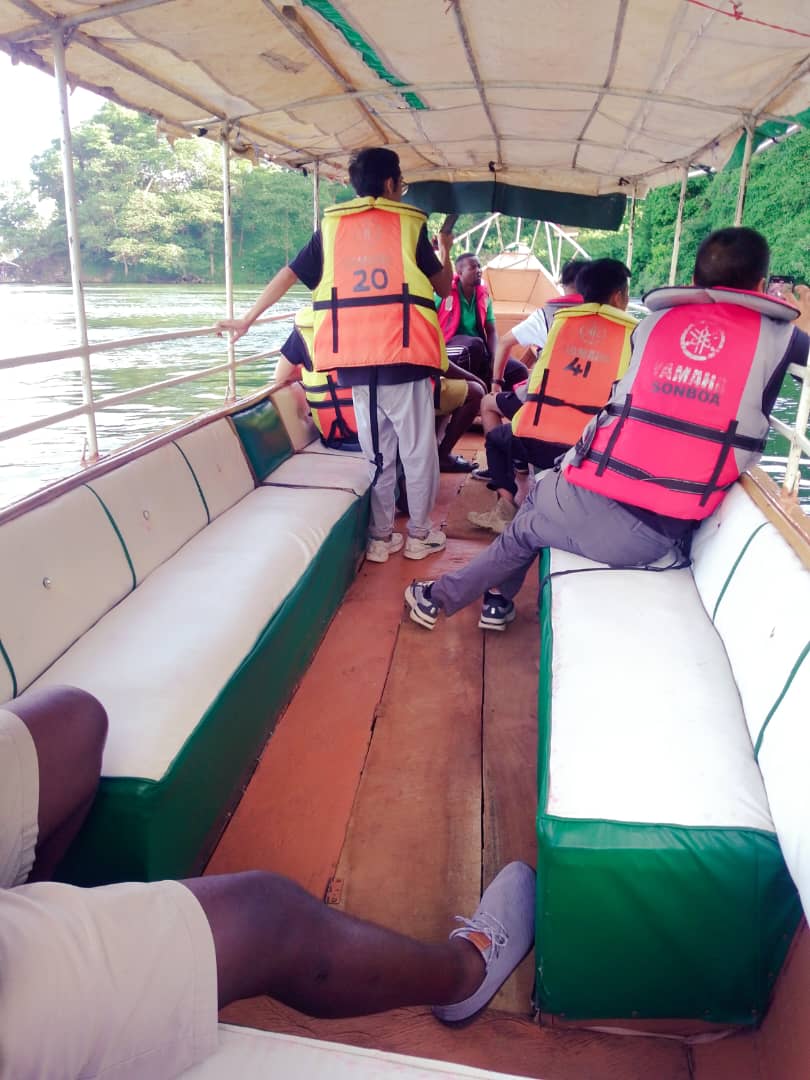Guests aboard a wooden Nile cruise boat, lush green banks behind
