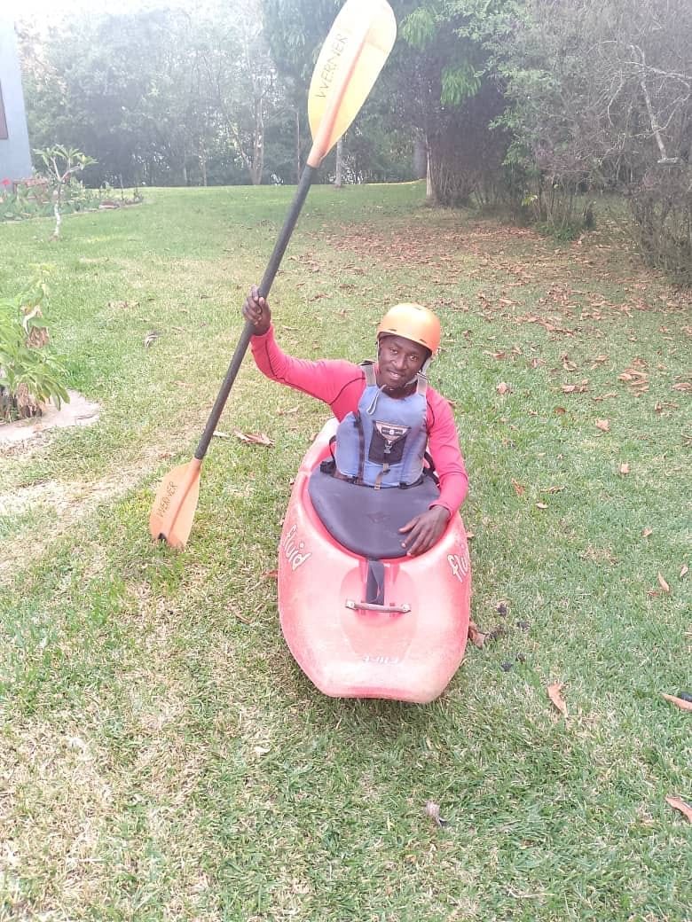 Mwango, adventure guide, raising his paddle from his kayak