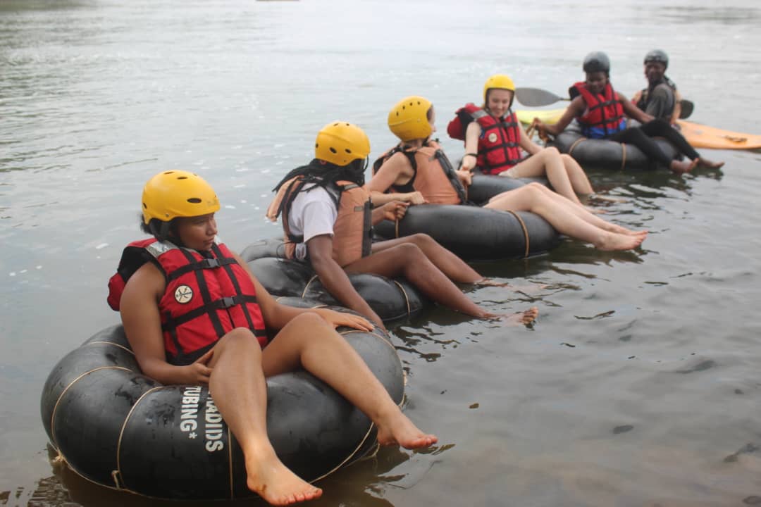 Six tubers lined up in yellow helmets and red life vests with a kayak guide